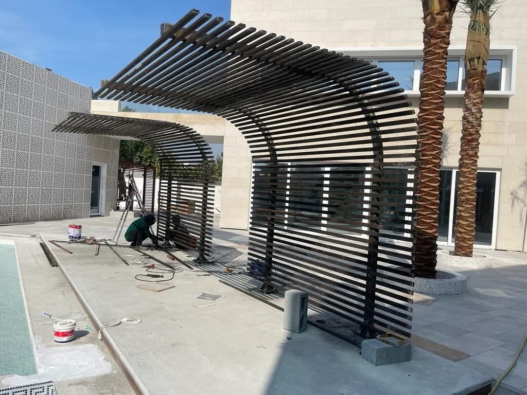 Curved black slatted shade beside a pool